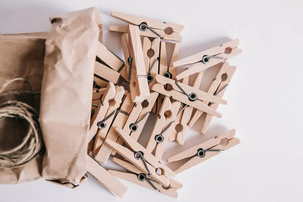 Wooden clothespins in paper bag with rope on white background. View from above. Place for your text.