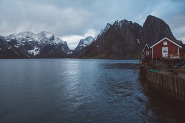 Norveç evleri ve dağları fiyort üzerindeki kayalar İskandinav seyahat manzarası Lofoten adaları.