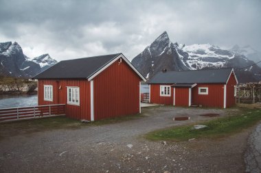 Norveç evleri ve dağları fiyort üzerindeki kayalar İskandinav seyahat manzarası Lofoten adaları.