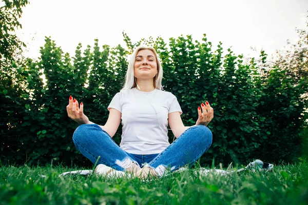 Beautiful Blonde Girl Headphones Sits Meditative Pose Listening Music Green — Stock Photo, Image