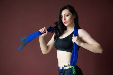 Mavi kemerli güzel atletik kadın portresi. Dövüş sanatları konsepti. İçerde, stüdyoda, arka planda fotokopi alanı reklamında..