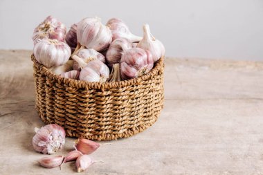 Tahta bir arka planda hasır sepette sarımsak. Kopyala, metin için boşluk.