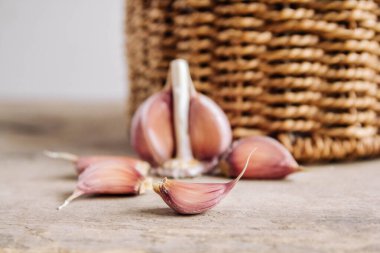 Tahta bir arka planda hasır sepette sarımsak. Kopyala, metin için boşluk.