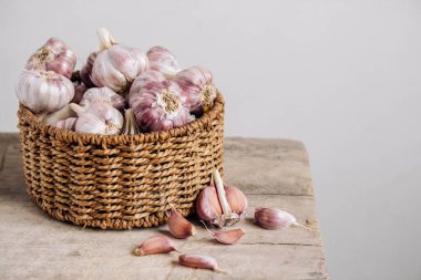 Tahta bir arka planda hasır sepette sarımsak. Kopyala, metin için boşluk.