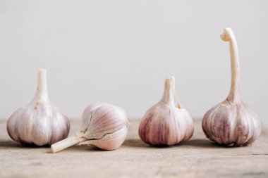Sarımsaklar ahşap bir arka planda bir sırada yatıyor. Kopyala, metin için boşluk.