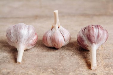 Sarımsaklar ahşap bir arka planda bir sırada yatıyor. Kopyala, metin için boşluk.