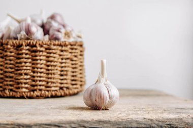 Tahta bir arka planda hasır sepette sarımsak. Kopyala, metin için boşluk.