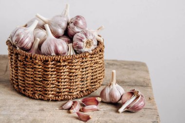 Tahta bir arka planda hasır sepette sarımsak. Kopyala, metin için boşluk.