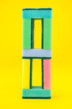 Sarı arka planda katlanmış piramidi temizlemek için çok renkli süngerler. Metin için boşluk.