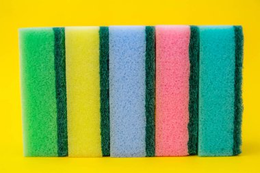 Sarı arka planda bulaşık yıkamak ve temizlemek için çok renkli köpük kauçuk sünger. Üst görünüm, desen.