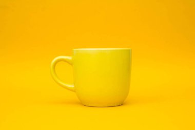 Sarı arka planda sarı seramik bardak. Kahve ya da çay için boş sarı bardak. Metin için boşluk.