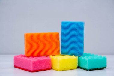 Beyaz bir masada bulaşık yıkamak ve temizlemek için çok renkli süngerler. Metin için boşluk.