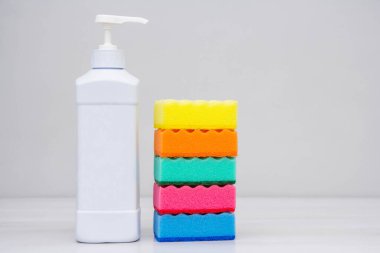 Beyaz bir masada bulaşık yıkamak için plastik şişe ve sünger. Temizlik malzemeleri. Metin için boşluk.