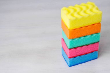 Beyaz bir masada bulaşık yıkamak ve temizlemek için çok renkli süngerler. Metin için boşluk.