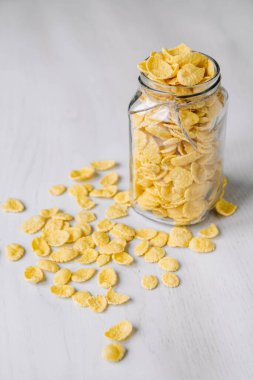 Beyaz ahşap yüzeyde cam bir kavanozda mısır gevreği. Metnin için yer.