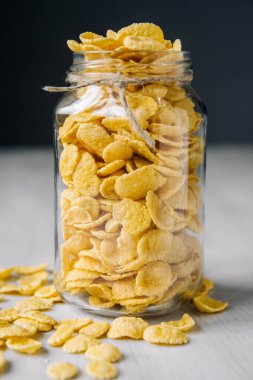 Beyaz ahşap yüzeyde cam bir kavanozda mısır gevreği. Metnin için yer.