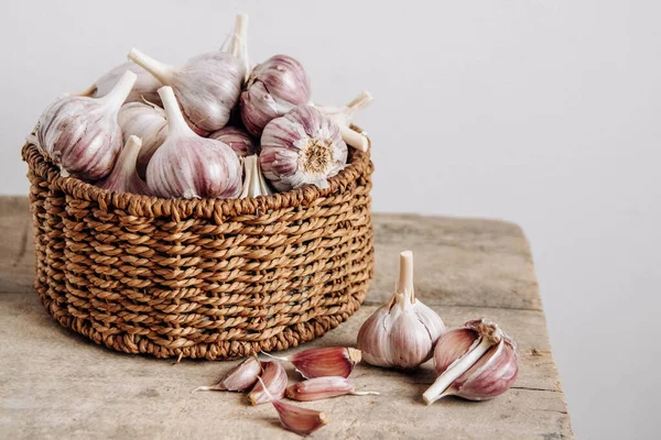 Tahta bir arka planda hasır sepette sarımsak. Kopyala, metin için boşluk.