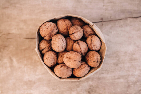 Walnuts in a paper bag on a old rustic table. Walnuts in a paper bag. Top view. Copy, empty space for text.