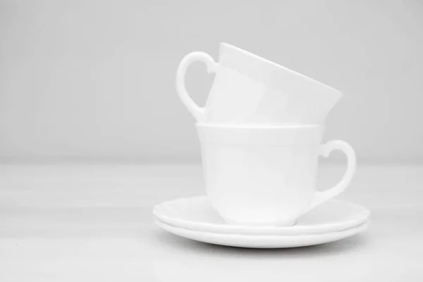 白いテーブルの上にソーサー付きの白いセラミックカップ テキストのスペース — ストック写真