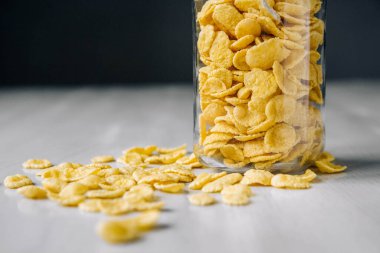 Beyaz ahşap yüzeyde cam bir kavanozda mısır gevreği. Metnin için yer.