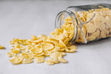 Beyaz ahşap yüzeyde cam bir kavanozda mısır gevreği. Metnin için yer.