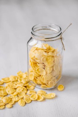 Beyaz ahşap yüzeyde cam bir kavanozda mısır gevreği. Metnin için yer.