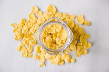 Beyaz ahşap yüzeyde cam bir kavanozda mısır gevreği. Üst Manzara. Metnin için yer.