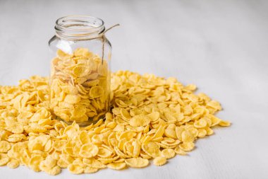 Beyaz ahşap yüzeyde cam bir kavanozda mısır gevreği. Metnin için yer.