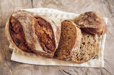 Tohumlu kahverengi taze ekmek eski ahşap arka planda parçalara ayrılır. Üst görünüm, alanı kopyala.