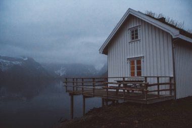 Norveç evleri ve dağları fiyort üzerindeki kayalar İskandinav seyahat manzarası Lofoten adaları.
