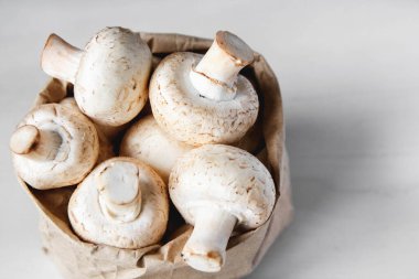 Beyaz tahta bir masada, kağıt torbada mantar şampiyonları. Kapatın. Metin veya reklam için yer.