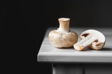 İki mantar şampiyonu arka planda beyaz bir masada sıralanmış yatıyor. Mesaj ya da reklam için yer. Kenarlık tasarla.