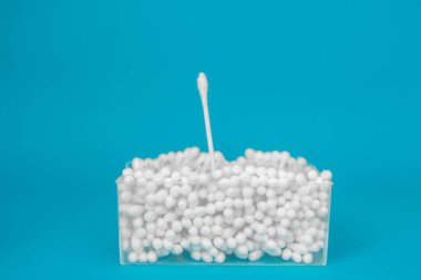 Plastik şeffaf dikdörtgen kapta pamuk tomurcukları ve mavi arka planda ayrı ayrı birkaç pamuk tomurcukları. Metin iletiniz ya da tanıtım içeriğiniz için boşluk.