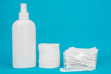 Pamuk pedler, plastik şişe ve mavi arka planda pamuk tomurcukları. Spa konsepti. Pamuk Kozmetik Makyaj Tamponları. Kopyala, metin için boşluk.