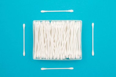 Plastik şeffaf dikdörtgen kapta pamuk tomurcukları ve mavi arka planda ayrı ayrı birkaç pamuk tomurcukları. Metin iletiniz ya da tanıtım içeriğiniz için boşluk.