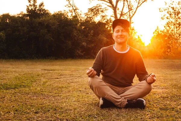 Mladý Pohledný Muž Meditativní Poloze Sedí Trávníku Pozadí Lesa Západu — Stock fotografie