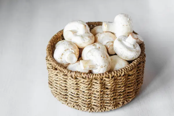 Cogumelos Champinhons Uma Cesta Vime Redonda Uma Mesa Madeira Branca — Fotografia de Stock
