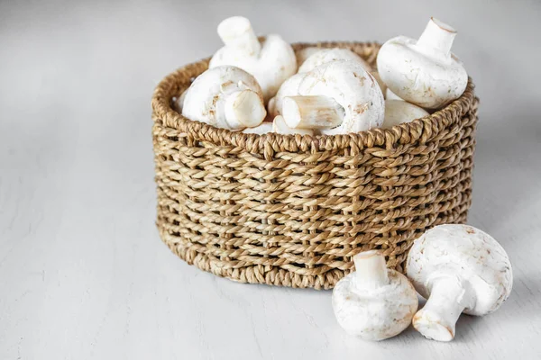 Cogumelos Champinhons Uma Cesta Vime Redonda Uma Mesa Madeira Branca — Fotografia de Stock