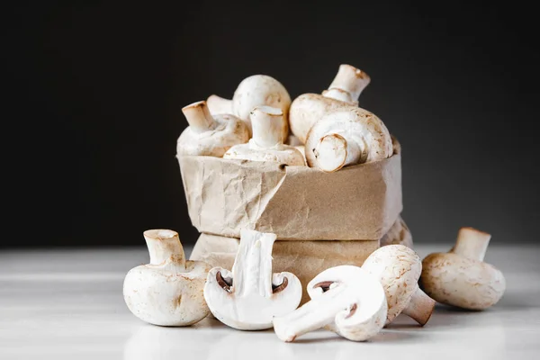 Cogumelos Champinhons Saco Papel Uma Mesa Madeira Branca Fundo Escuro — Fotografia de Stock