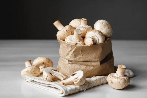 Cogumelos Champinhons Saco Papel Uma Mesa Madeira Branca Fundo Escuro — Fotografia de Stock