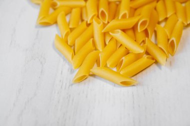 Beyaz ahşap arka planda makarna penne rigate. Üst görünüm, alanı kopyala.
