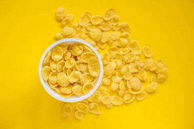 Sarı arka planda beyaz kasede mısır gevrekleri. Üst Manzara. Kopyala, metin için boşluk.