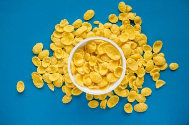 Mavi arka planda beyaz kasede mısır gevrekleri. Üst Manzara. Kopyala, metin için boşluk.