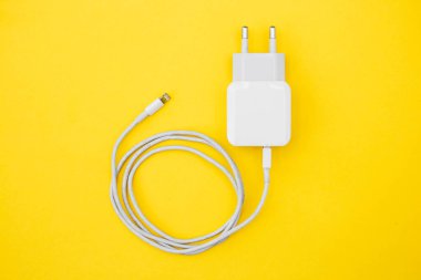 Sarı arka planda mobil şarj aleti ve USB kablosu. Üst Manzara. Kopyala, metin için boşluk.