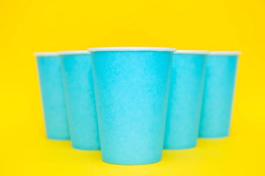 Sarı arka planda tek kullanımlık mavi bardaklar piramidi. Partiye hazırız. Kopyala, metin için boşluk.