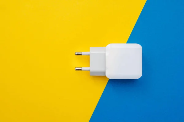 Mobile charger on yellow and blue background. Top view. Copy, empty space for text.