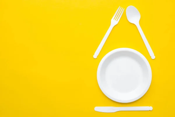 塑料白色叉子 勺子和盘子 黄色背景 顶部视图 简约主义风格 空的文字空间 — 图库照片