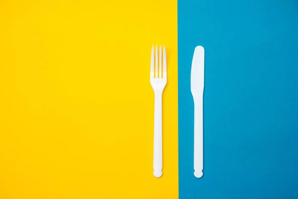 Λευκό Πλαστικό Πιρούνι Και Μαχαίρι Κίτρινο Και Μπλε Φόντο Μαγειρικό — Φωτογραφία Αρχείου
