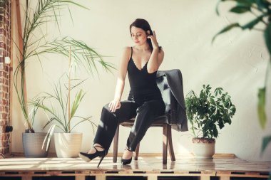 Siyah elbiseli güzel bir manken çatı katı tarzı bir sandalyede oturur..