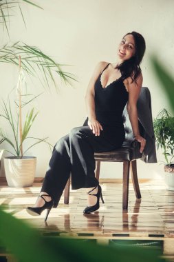Siyah elbiseli güzel bir manken çatı katı tarzı bir sandalyede oturur..